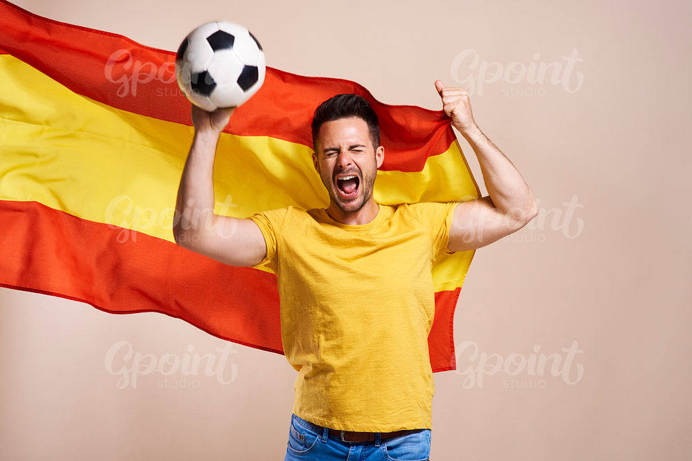Screaming Spanish fan holding flag and soccer ball