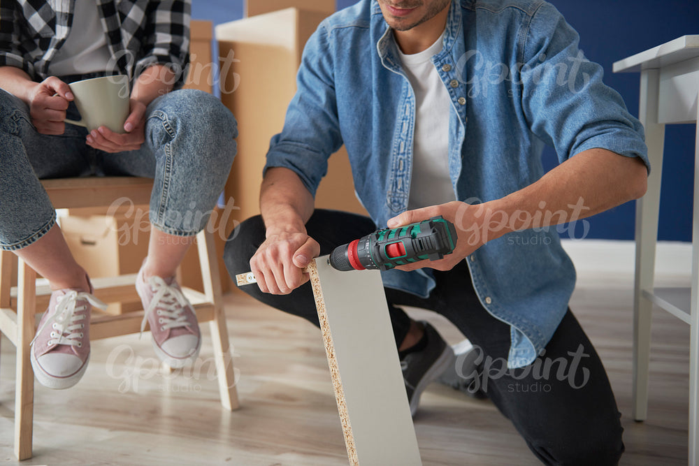 Man installing white furniture with electronic drill