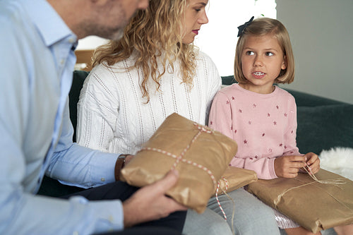 Caucasian family of parents and girl sitting and holding Christmas presents
