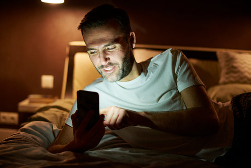 Man using a mobile phone and lying on the bed