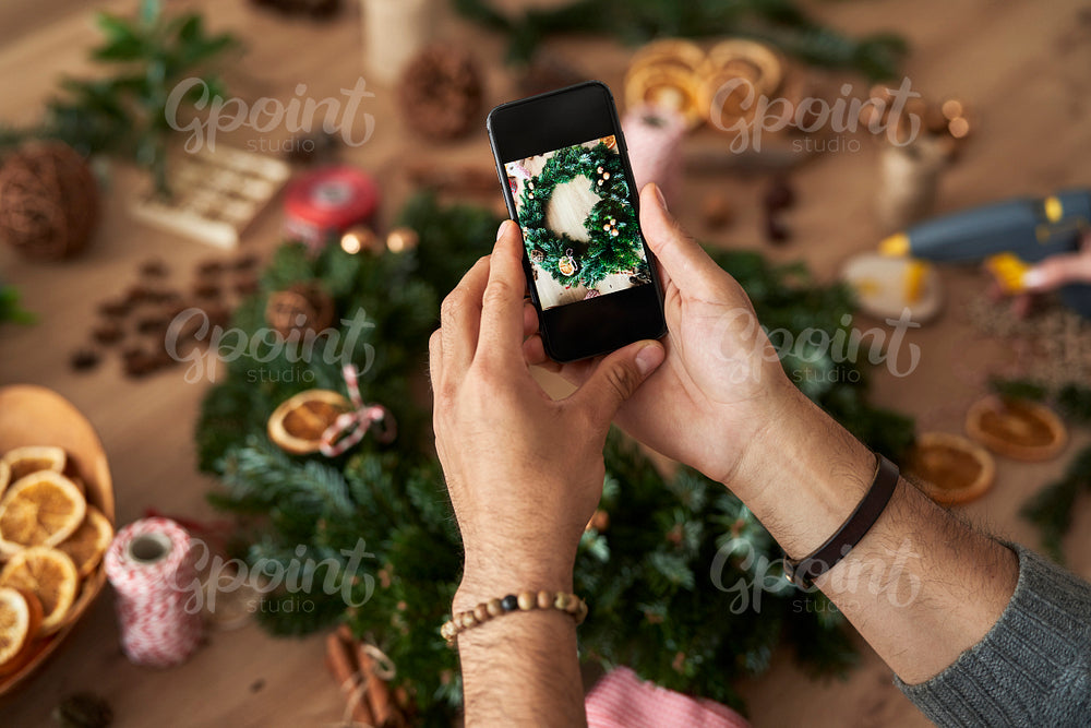 Top view of man taking photos of the Christmas wreath