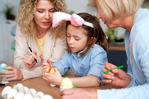 Girl with grandma and mother decorating Easter eggs together