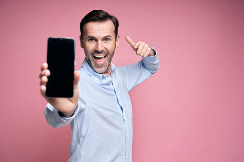 Happy man showing screen of mobile phone