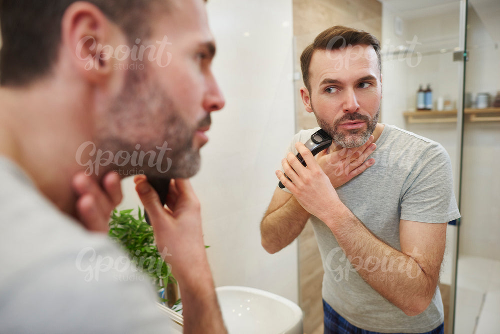 Man with electric razor shaving