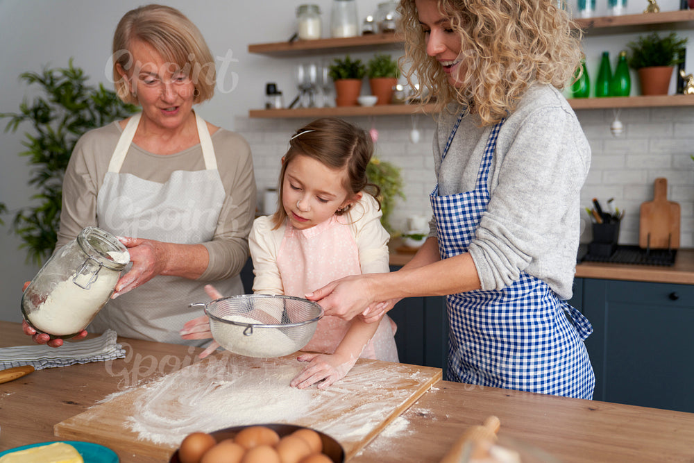 Smiling women sift the flour for Easter baking
