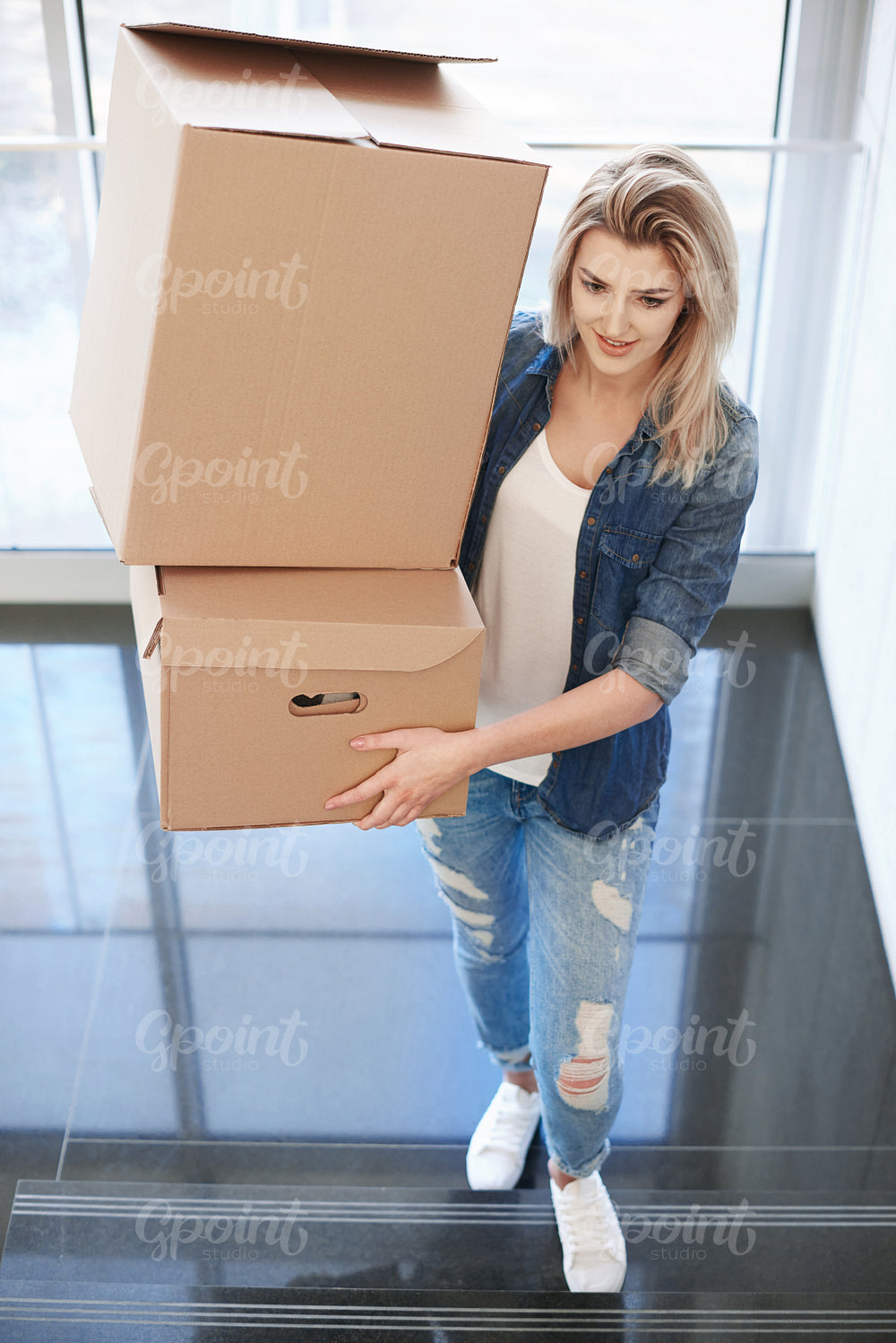Woman carrying cardboard box upstairs