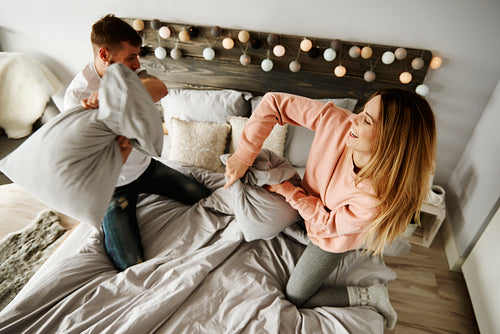 Couple fighting with pillows in bedroom