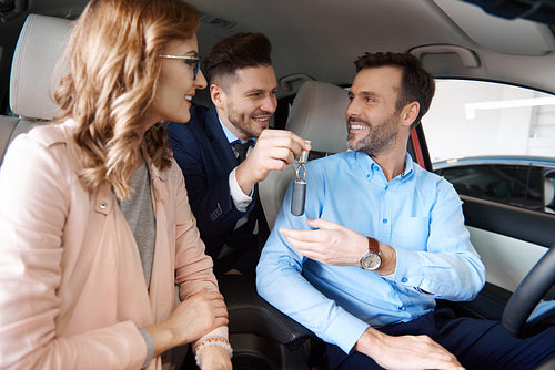 Mid adult couple with salesman inside the car