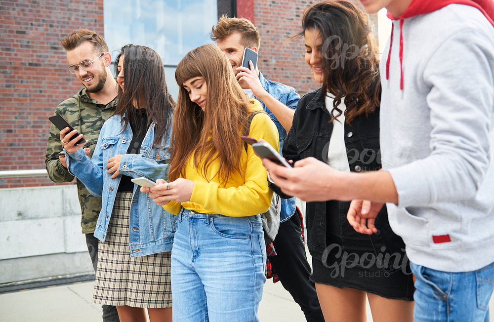 Young people with mobile phones standing in a row