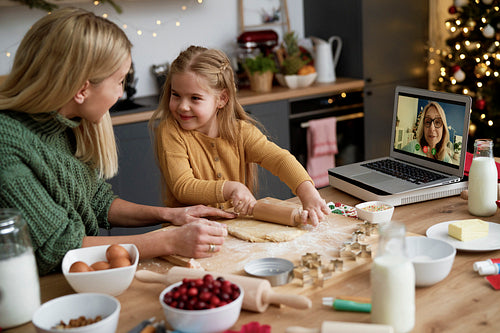 Mother and daughter preparing Christmas cookies during video conference