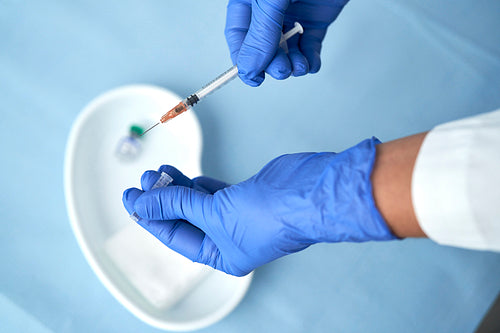 Top view of hands in protective gloves with vaccination equipment