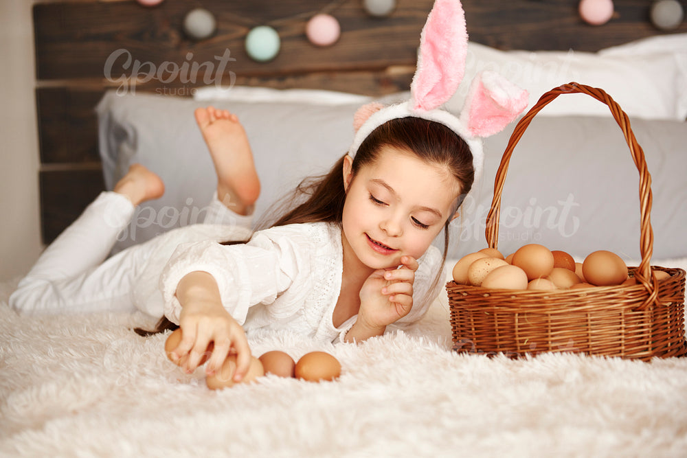 Happy child playing with eggs in bedroom