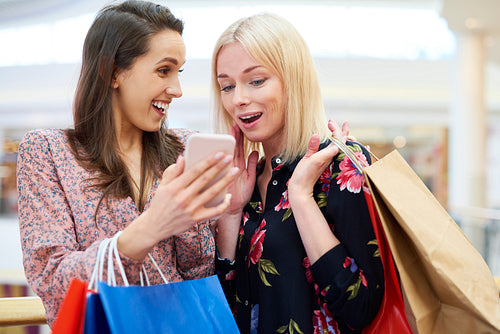 Girls with mobile phone choosing the next direction of shopping