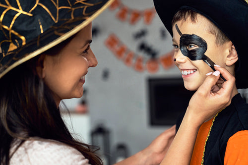 Mom painting face her son to Halloween's party