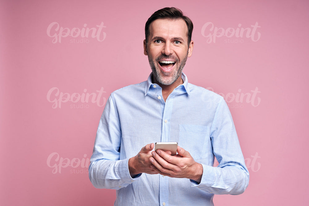 Smiling man holding mobile phone in hands 