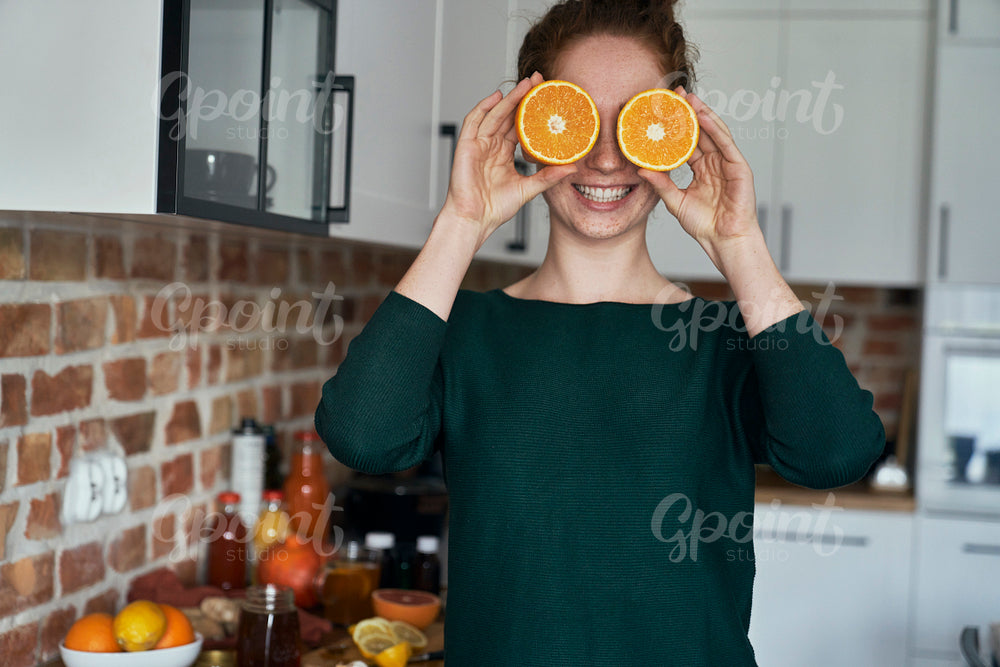 Caucasian young woman covering eyes with orange halves 
