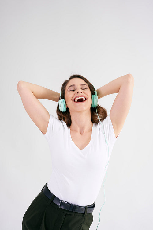 Joyful woman with headphones listening to music in studio shot