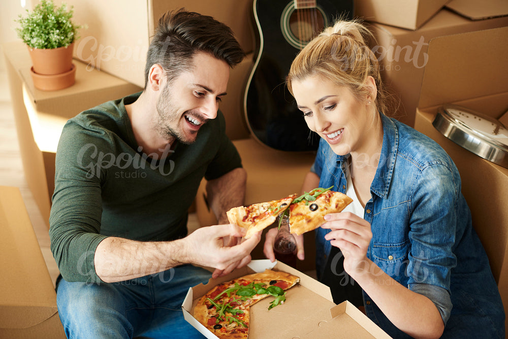 Couple eating pizza next to moving boxes