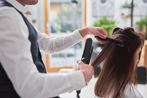 Female hairdresser using comb and straightener