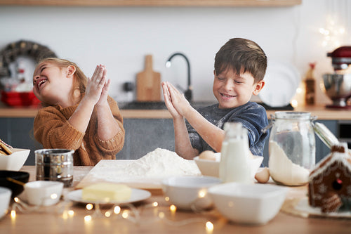 Children clasping using flour while baking cookies for Christmas