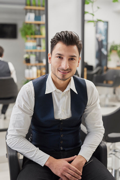 Portrait of smiling male customer sitting in hair salon