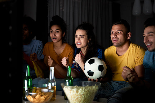 Group of friends cheering in front TV in the evening