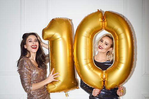 Beautiful women with golden balloons building the figure „10”