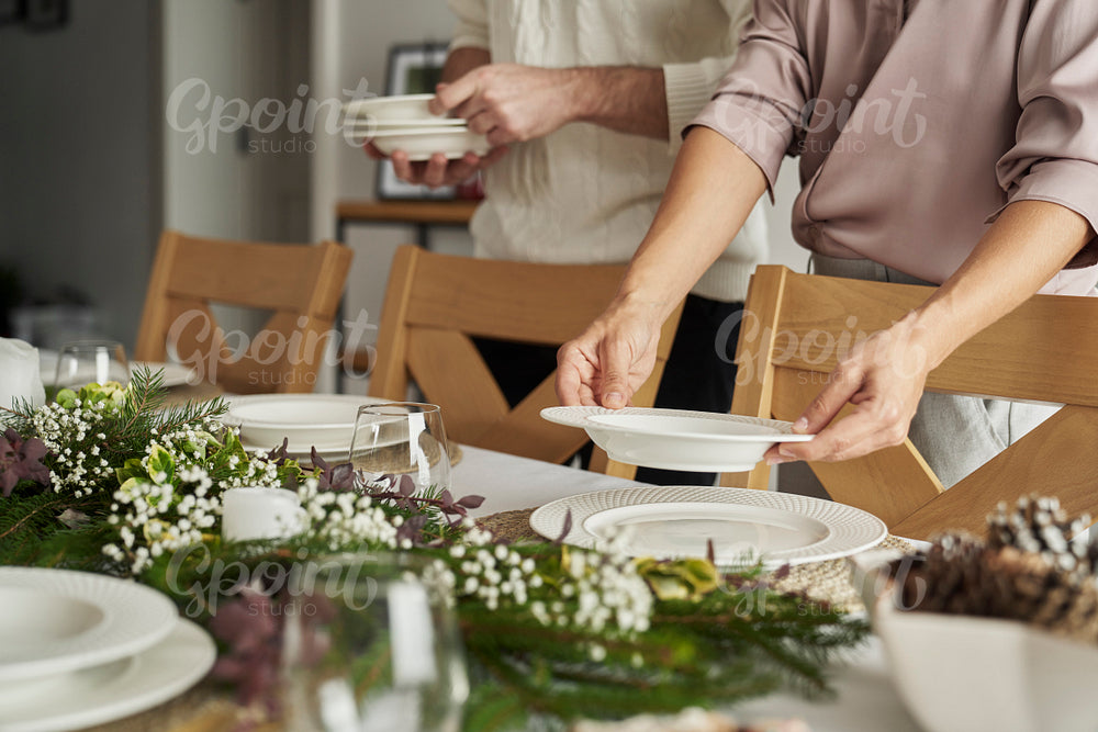 Unrecognizable caucasian people lying the  table for Christmas dinner 