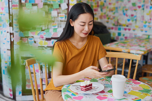 Young Vietnamese woman looking at mobile phone in a cafe