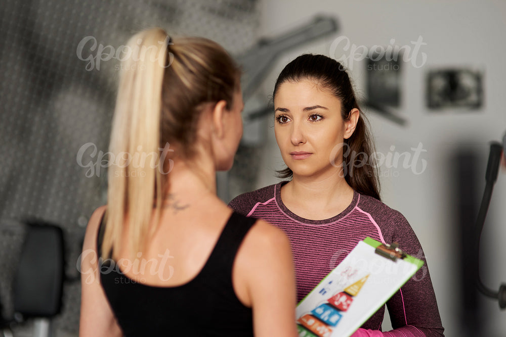 Fitness instructor and woman chatting before gym session