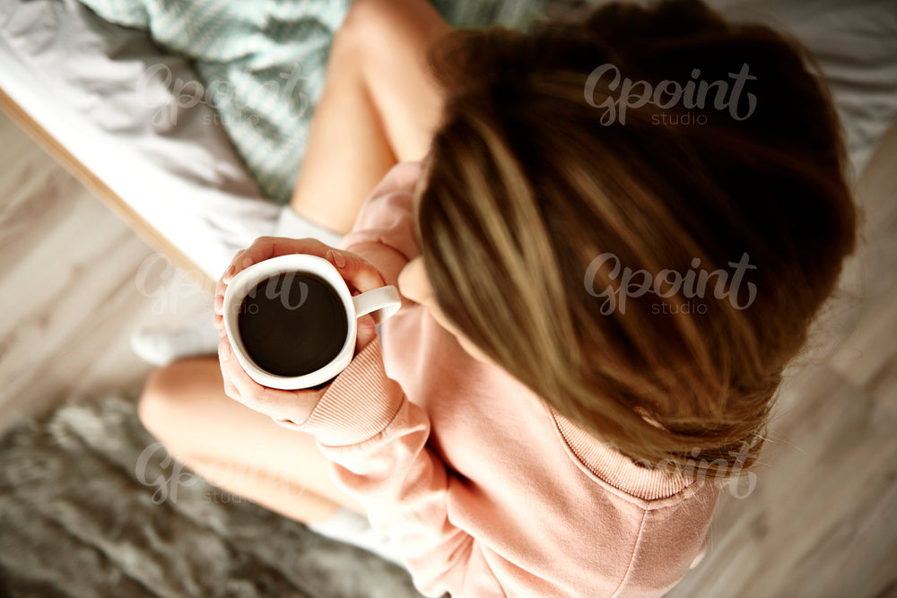 Unrecognizable woman drinking coffee in bed