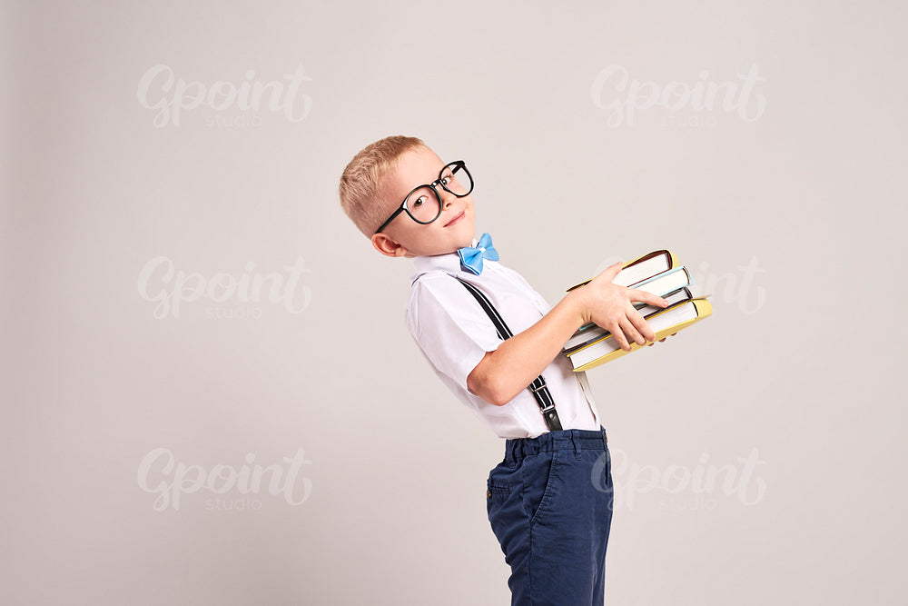 Side view of boy holding a stack of books