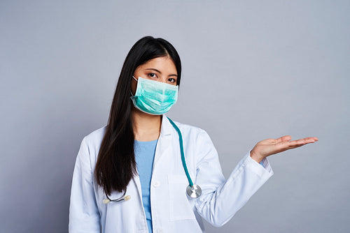 Doctor in face mask presenting something next to her