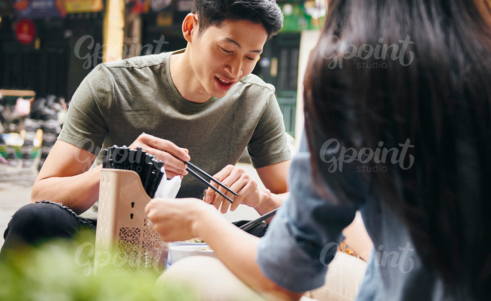 Young couple eating vietnamese food in the city street