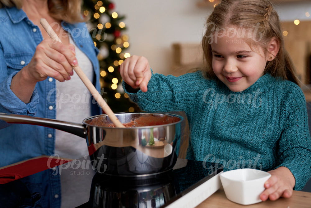 Little girl seasoning the homemade dish while Christmas cooking