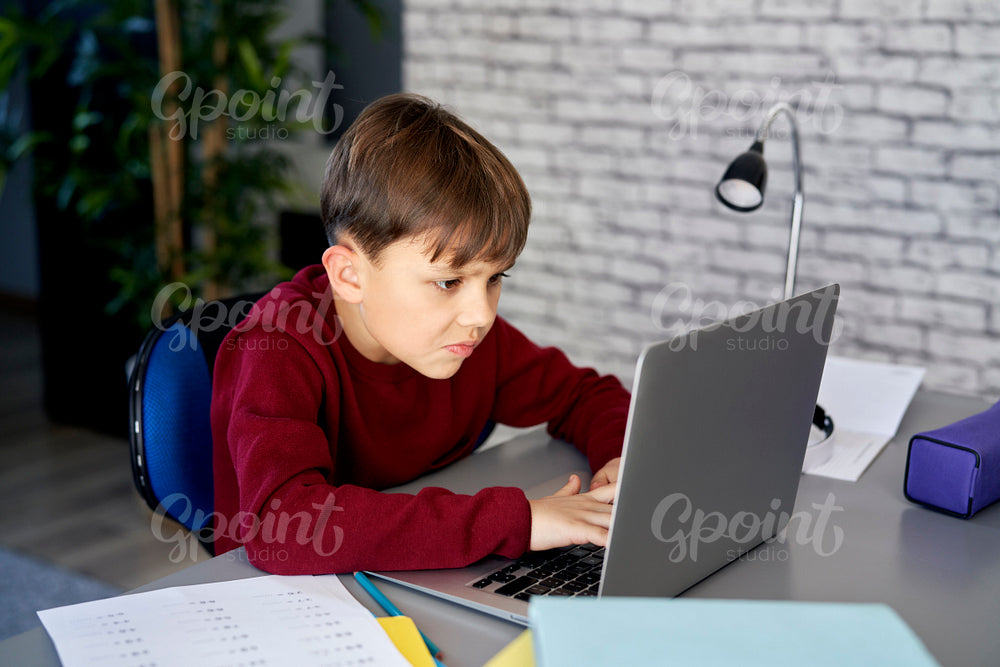 Concentrated boy using laptop during education