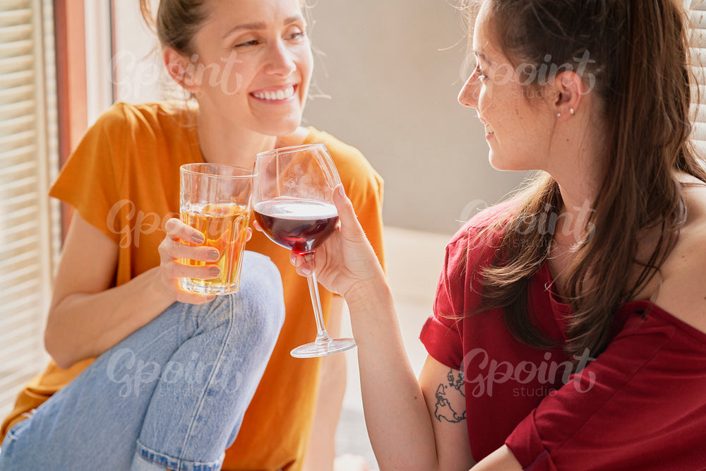 Two friends spending time together drinking wine and juice