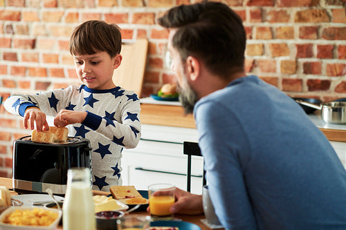 Son helps to prepare breakfast for himself and father