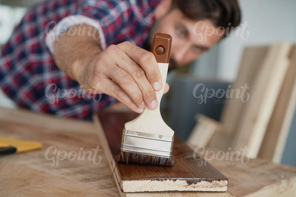 Close up of man painting boards with a brush