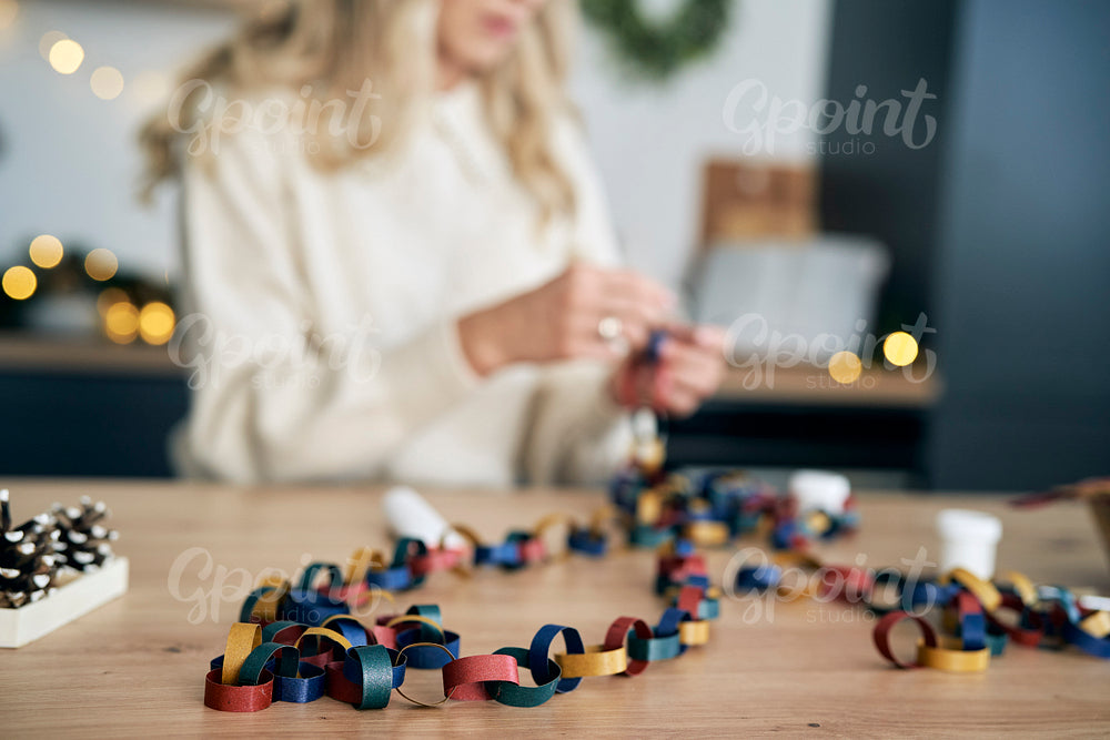 Selective focus of caucasian woman making DIY paper chain for Christmas tree 