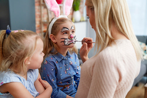 Mom painting Easter bunny on her daughter's face