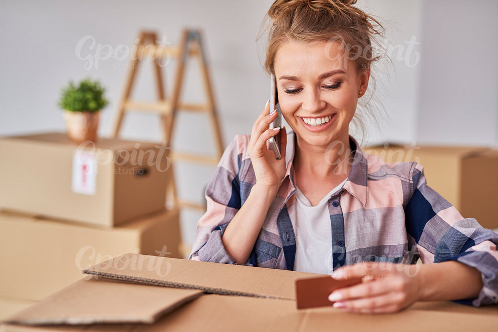 Smiling woman using phone while moving house