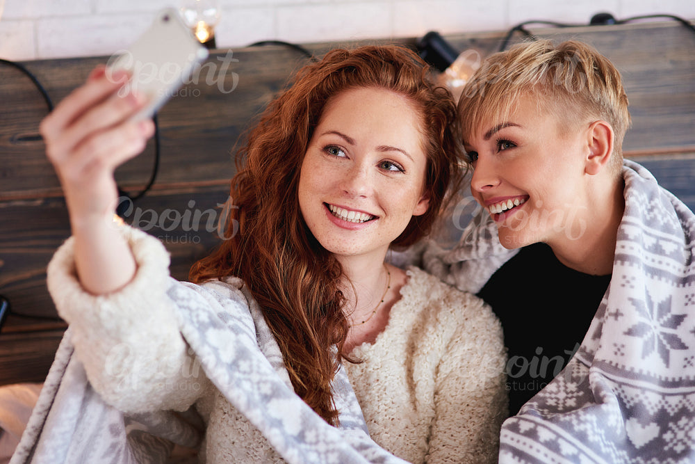 Female friends making a selfie in bedroom