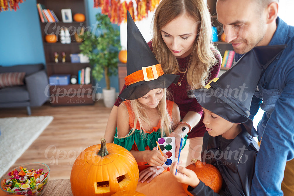 Family painting on orange pumpkins