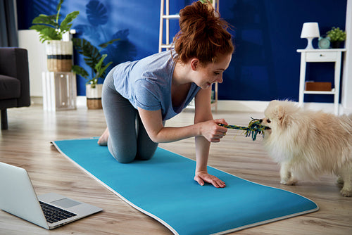 Woman playing with dog while exercising at home