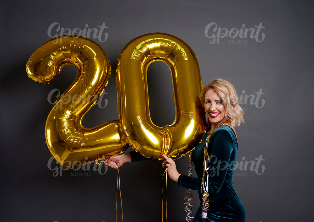 Woman with golden balloons building the figure „20”