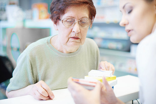 Senior woman with pharmacist at checkout desk