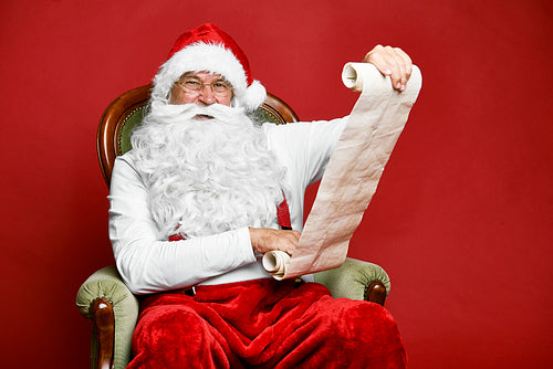Smiling caucasian Santa Claus reading Christmas's letter