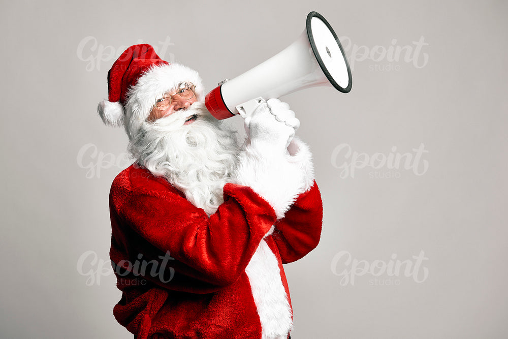 Caucasian Santa Claus talking by megaphone on grey background 