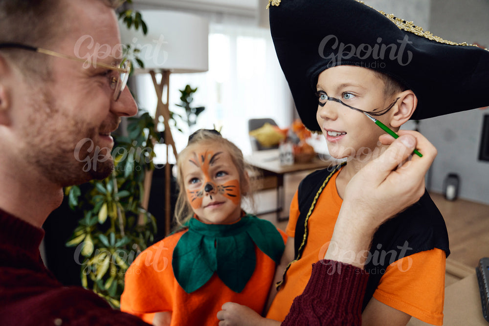 Dad helping his kids to prepare to Halloween